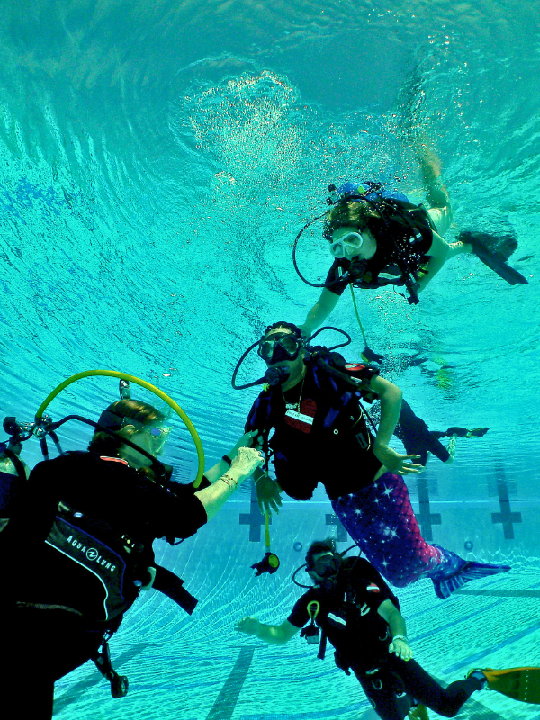 Therapeutic scuba diving helping adaptive diver in mermaid tail build confidence